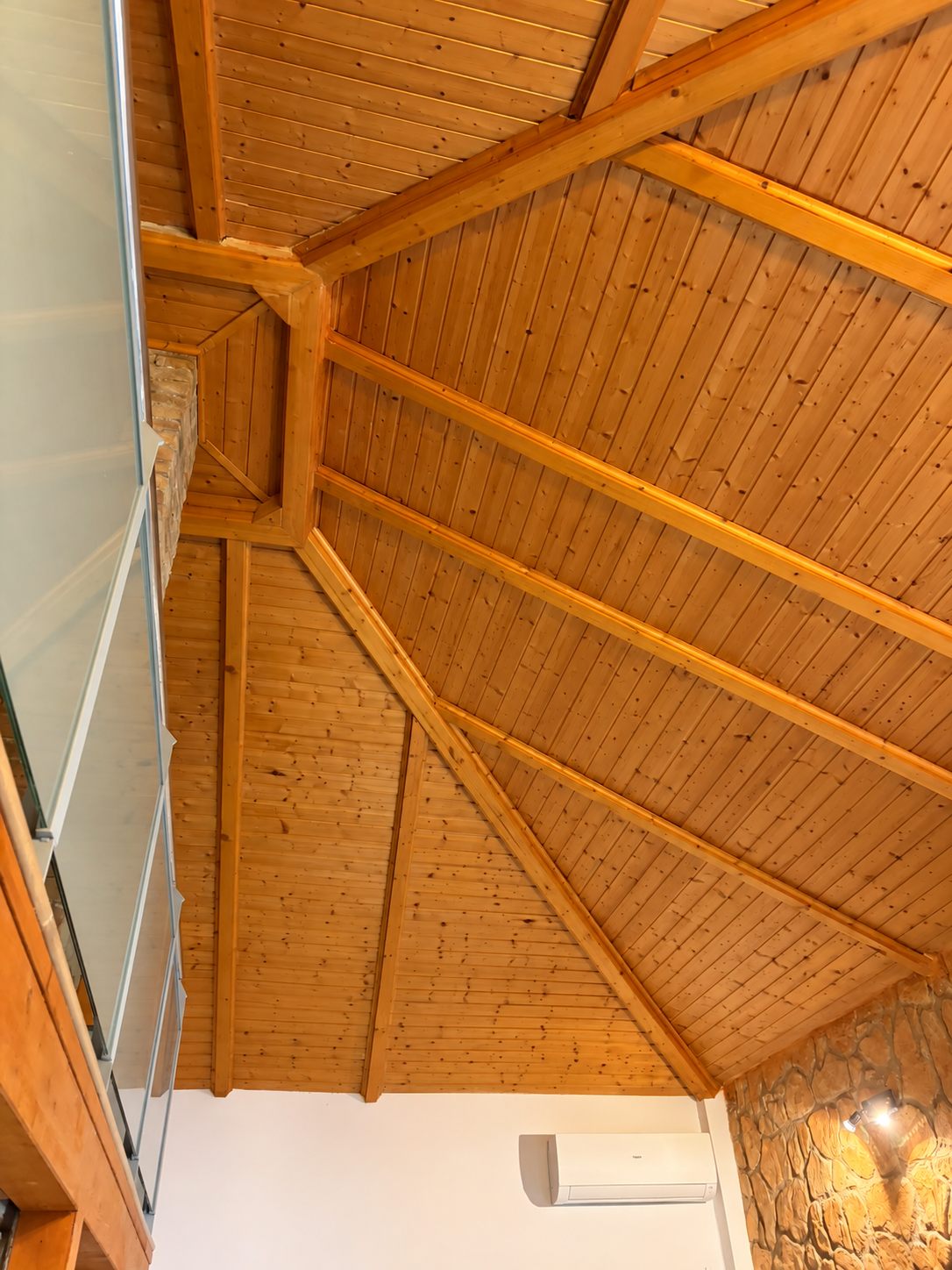 Geometría compleja de vigas, encuentros y revestimiento de madera en la cubierta